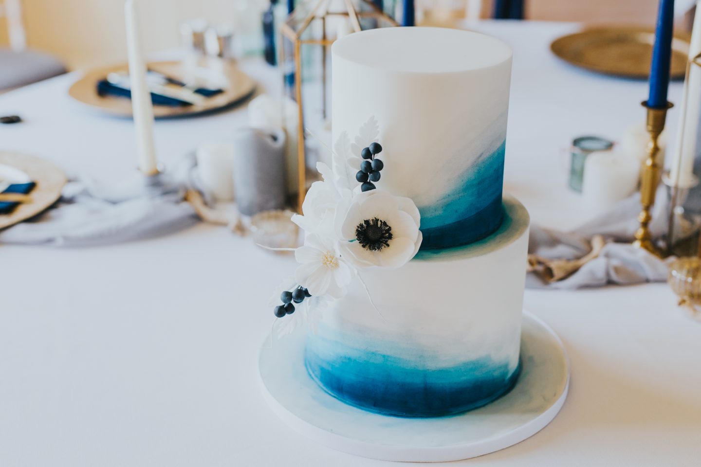 Blue ombre two tier wedding cake with white sugar crafted flowers.