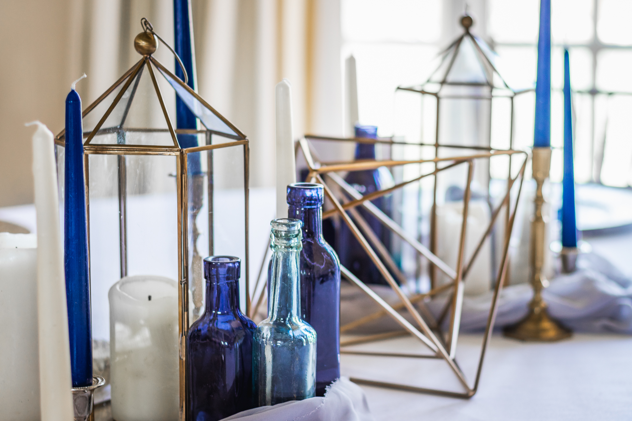 wedding styling showing blue candles, bottles and gold geometric shapes.